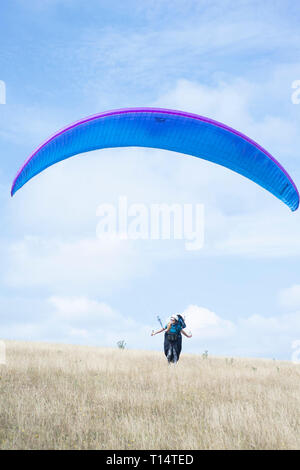 Une jeune femme para planeur décolle de la South Downs. Banque D'Images