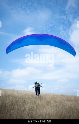 Une jeune femme para planeur décolle de la South Downs. Banque D'Images