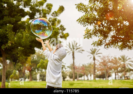 Mignon enfant mâle les captures des bulles de savon dans la nature Banque D'Images