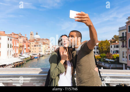 L'Italie, Venise, happy young couple sur un pont en tenant un selfies Banque D'Images