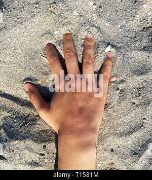 La main de femme faisant un dessin dans le sable avec sa main tendue au cours de ses vacances d'été dans les îles Cook. Banque D'Images