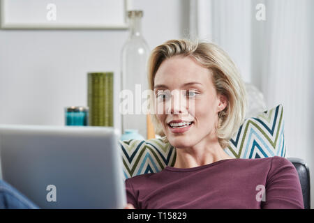 Jeune femme avec tablet lying on couch at home Banque D'Images