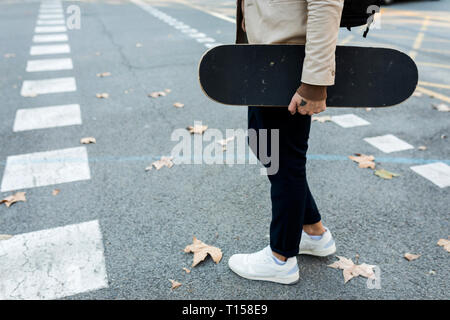 Homme avec sac à dos et à roulettes de traverser la rue en automne, vue partielle Banque D'Images