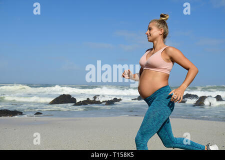 Smiling pregnant woman jogging sur la plage Banque D'Images