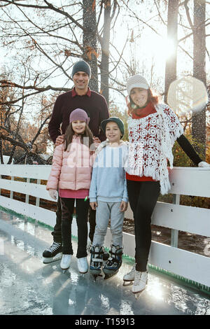 Famille leaning on railing à la patinoire Banque D'Images