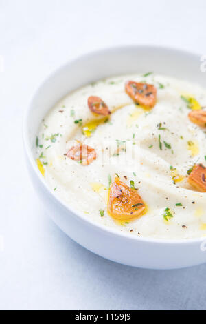 Gros plan d'une purée de chou-fleur Chou-fleur et végétalien en purée. L'ail rôti sur le dessus de la purée de chou-fleur blanc et de thym dans un bol blanc. White backgroun Banque D'Images