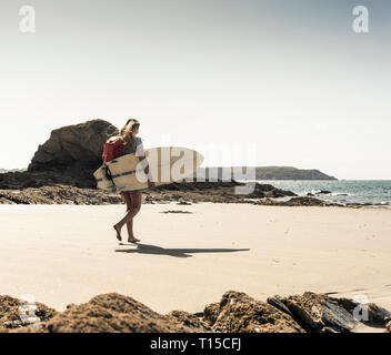 Jeune femme avec sac à dos, la marche sur la plage, l'exécution de surf Banque D'Images