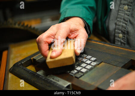 Un homme nettoie un alphabet de type métal avec un pinceau Banque D'Images