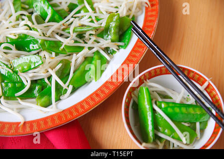 Assiette de légumes sautés et d'un servant dans un bol chinois avec des baguettes Banque D'Images