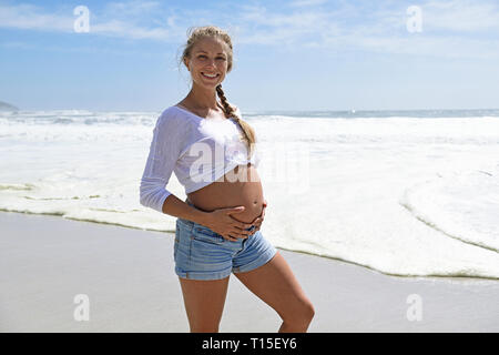 Portrait of smiling pregnant woman on the beach Banque D'Images