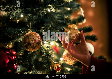 Femme hand holding golden Christmas bauble, close-up Banque D'Images