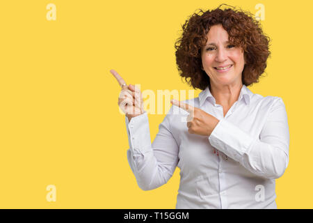 Beau milieu des affaires senior femme ager sur fond isolé en souriant et regardant la caméra pointant à deux mains et les doigts sur le côté Banque D'Images