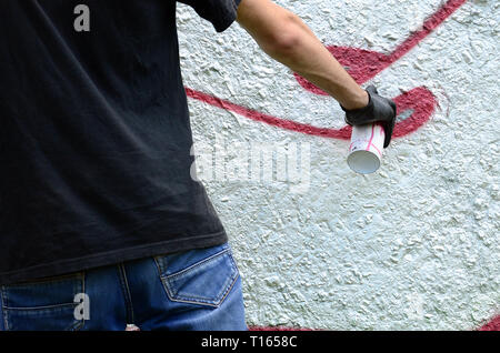 Un jeune voyou peint des graffitis sur un mur en béton. Vandalisme illégaux concept. Street art. Banque D'Images