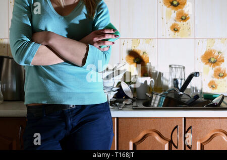 Fragment d'un corps de femme au comptoir de la cuisine, rempli de beaucoup de plats sales. La fille est fatigué de faire face à l'obligation quotidienne de lave-d Banque D'Images