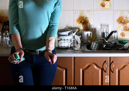 La fille menotté, mécontents et las de la vaisselle à la main tous les jours, se trouve à côté du comptoir de la cuisine et un puits qui est rempli d'un rack d'onu Banque D'Images