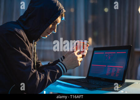 Homme hacker dans le capot de tenir le téléphone dans ses mains essayant de voler des bases de données Access avec des mots de passe. Le concept de sécurité cybernétique Banque D'Images