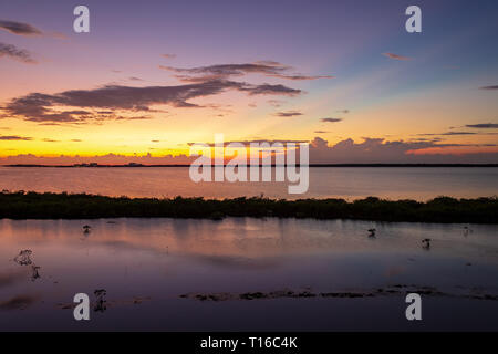 Le soleil se couche sur la baie de Chetumal sur Ambergris Caye, Belize casting teintes brillantes dans le ciel et se reflétant dans les eaux a ondulé par une brise chaude. Banque D'Images