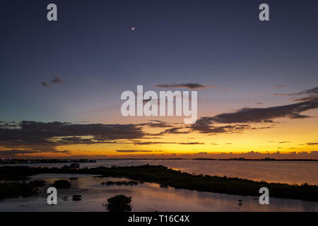 Le soleil se couche sur la baie de Chetumal sur Ambergris Caye, Belize casting teintes brillantes dans le ciel et se reflétant dans les eaux a ondulé par une brise chaude. Banque D'Images