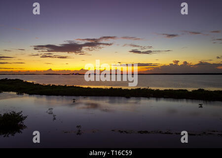 Le soleil se couche sur la baie de Chetumal sur Ambergris Caye, Belize casting teintes brillantes dans le ciel et se reflétant dans les eaux a ondulé par une brise chaude. Banque D'Images