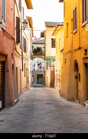 Chiusi, Italie rue vide dans petite ville village de Toscane vue verticale étroite durant la journée avec orange lumineux jaune vibrant vif des murs couleur Banque D'Images