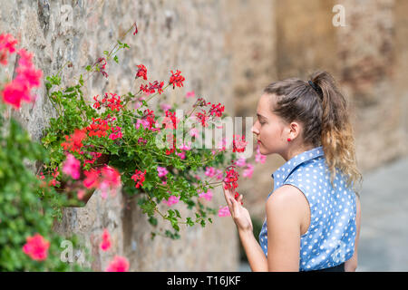 Monticchiello, Italie Ville ou village ville de Toscane de gros plan femme jeune girl smelling red toucher les pots de fleurs décorations sur pierre de jour d'wal Banque D'Images