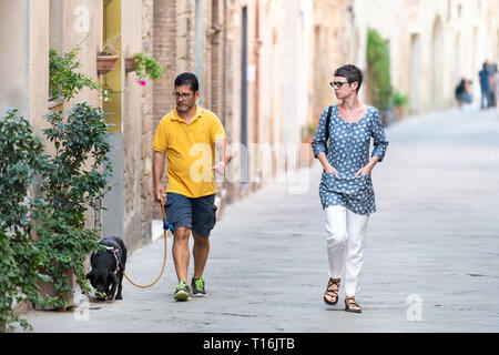 Montalcino, Italie - 26 août 2018 : Petite ville médiévale, village de Toscane aux beaux jours et les gens couple walking dog leash Banque D'Images