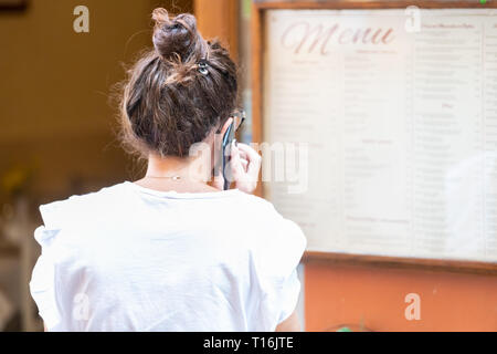 Montalcino, Italie - 26 août 2018 : Petite ville médiévale village de Toscane et les gens parler au téléphone mobile lecture menu Se connecter par restaurant Banque D'Images