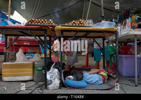 Mère au travail. Enfant endormi sous ses mères food. La Thaïlande, en Asie du sud-est Banque D'Images