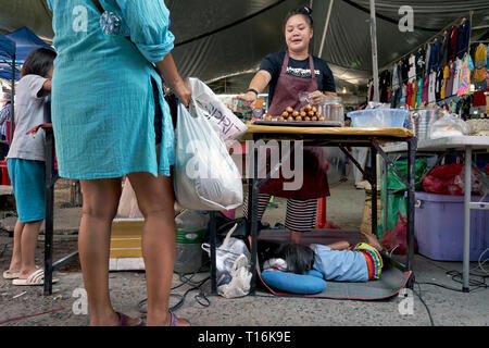 Mère au travail. Enfant endormi sous ses mères food. La Thaïlande, en Asie du sud-est Banque D'Images