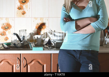 Fragment d'un corps de femme au comptoir de la cuisine, rempli de beaucoup de plats sales. La fille est fatigué de faire face à l'obligation quotidienne de lave-d Banque D'Images