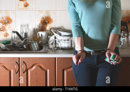 La fille menotté, mécontents et las de la vaisselle à la main tous les jours, se trouve à côté du comptoir de la cuisine et un puits qui est rempli d'un rack d'onu Banque D'Images