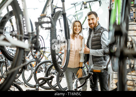 Vendeur aider les jeunes femme de choisir un nouveau vélo pour acheter l'article dans le magasin de bicyclettes Banque D'Images