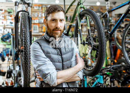 Portrait d'un bel homme comme un acheteur ou un vendeur en magasin de bicyclettes Banque D'Images