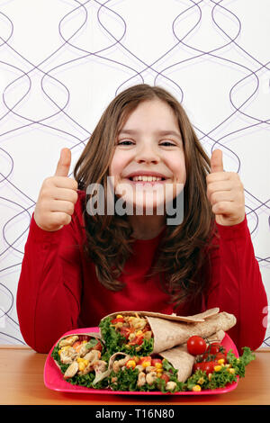 Happy little girl avec burritos mexican food et Thumbs up Banque D'Images