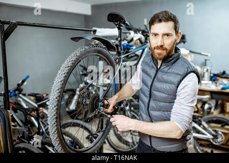 Servant un réparateur beau vélo, régler certains dysfonctionnements, le sélecteur de vitesse à l'atelier Banque D'Images