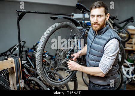 Servant un réparateur beau vélo, régler certains dysfonctionnements, le sélecteur de vitesse à l'atelier Banque D'Images