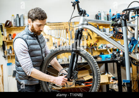 Servant un réparateur beau vélo, régler certains dysfonctionnements, à l'atelier à roue avant Banque D'Images