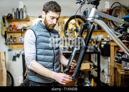 Servant un réparateur beau vélo, régler certains dysfonctionnements, à fourche de vélo à l'atelier Banque D'Images