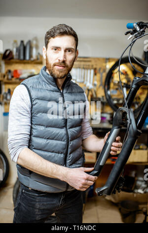 Portrait of a handsome réparateur au service d'une location, régler certains dysfonctionnements, à fourche de vélo à l'atelier Banque D'Images