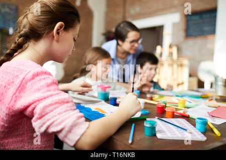 Vue arrière de Girl Painting in Art Class Banque D'Images