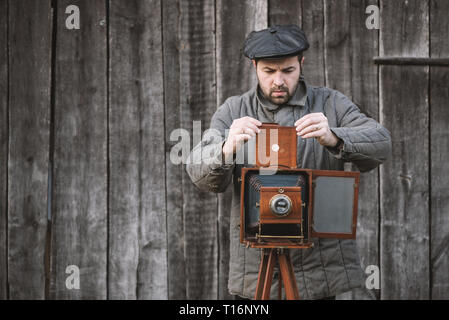 Photographe se prépare pour le tournage et l'insère dans le support film grand format rétro. Concept - Photographie des années 1930 aux années 1950. Banque D'Images