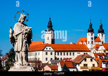 La Statue baroque de saint Jean Népomucène et Telc chateau avec église du saint Nom de Jésus en arrière-plan, Telc, région de Vysocina, République tchèque. Banque D'Images