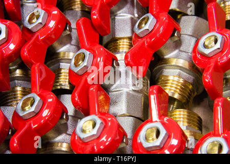 De nombreux robinets en laiton chromé avec une poignée rouge, conceptual image. Macro. Banque D'Images