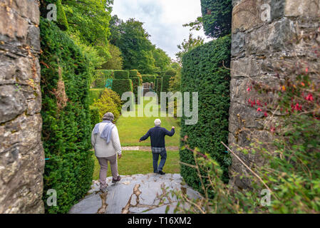 Deux visiteurs, l'homme et la femme en descendant étapes dans le jardin topiaire de Plas Brondanw, Gwynedd, au nord du Pays de Galles, Royaume-Uni Banque D'Images