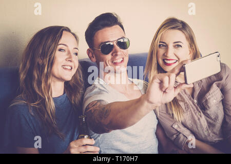 Deux jeunes filles et un jeune homme Ensemble de prendre une photo avec selfies téléphone cellulaire moderne à partager sur les réseaux sociaux compte - pour la technologie Banque D'Images