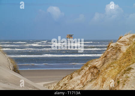 La plate-forme de production en mer près de l'île néerlandaise d'Ameland, dunes, plage et vagues à l'avant-plan Banque D'Images