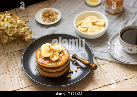 Pancakes à la banane, noix et miel, servi avec du thé. Style rustique. Banque D'Images