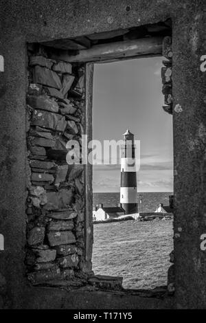 C'est une photo de St John's Point Lighthouse à travers une fenêtre de les ruines d'une ancienne station de la garde côtière sur la côte est de l'Irlande du Nord sur t Banque D'Images