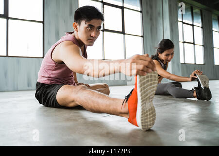 Asian young man doing jambes les étirements avant l'exercice de base Banque D'Images