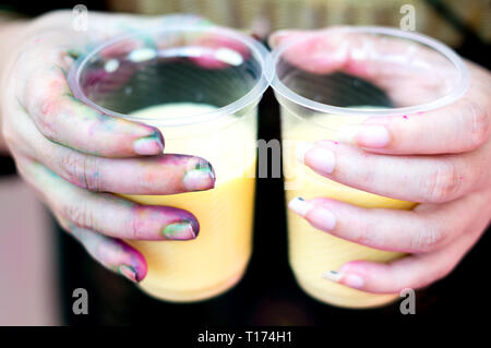 Colorful hands holding tasses jetables de thandai sur holi festival hindou Banque D'Images